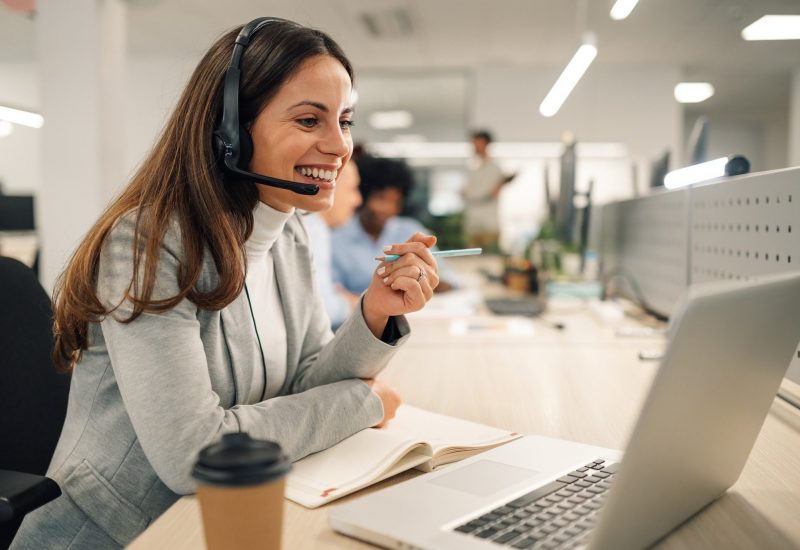 Caucasian business woman with headset working on a laptop in a call center